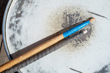 drumsticks lie on the surface of the drum. These sticks are old they have been repaired