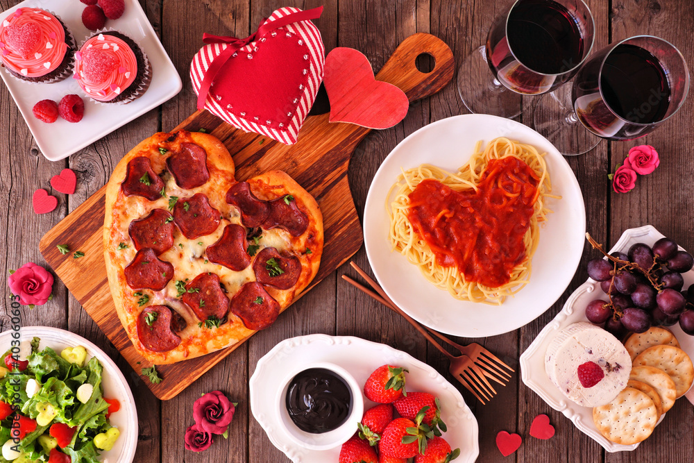 Poster home cooked valentines day dinner. top view table setting on a dark wood background. heart shaped pi