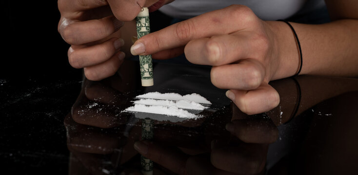Drug addict woman snorting cocaine powder with rolled dollar banknote. Narcotics concept. Close-up macro shot. Panoramic shot. Panorama banner. High resolution sharp photo.