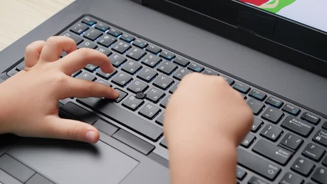 Top view of little boy typing and drawing on latop keyboard. Child using new technologies and computer in education at home