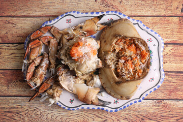 Open crab prepared to serve on a tray and on a wooden table