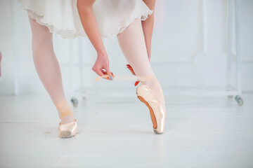 ballerina wears and ties ballet flats before ballet dance show, professional costume, the beauty of classical ballet.