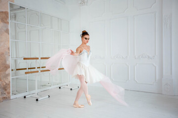 young ballerina in a white dress dancing in a bright studio