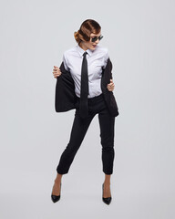 attractive woman with a retro hairstyle poses in a men's suit and sunglasses