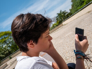 Fototapeta premium Photo of bored boy using his smartphone