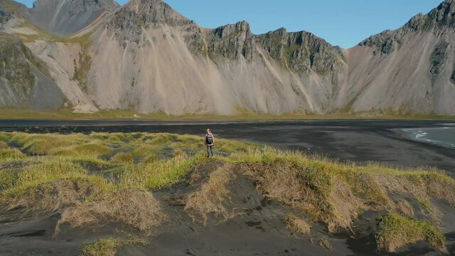 Epic drone view of the landscape in Stokksnes Iceland. Woman tourist looking to the Vestrahorn mountain. Nature travel and ecology concept.