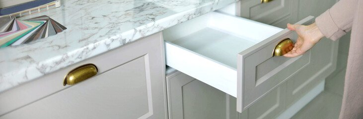 Banner Home improvement concept. young girl designer opens a drawer of a kitchen cabinet in a shop salon.