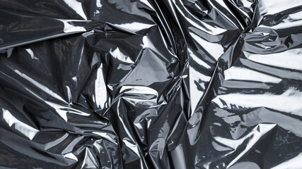 Plastic black background. Wrap transparent dark cellophane. Black shiny film bag pattern. Real...