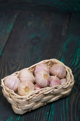 Garlic in a wicker basket. On green pine boards. Close-up shot.
