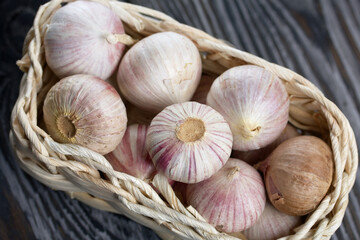 Garlic in a wicker basket. Close-up shot. On black pine boards.