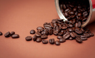 Organic, fair trade spilled coffee beans on brown background.