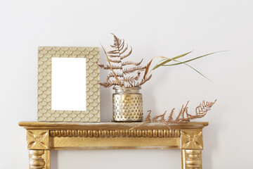 golden frame and dried plants  on white wall