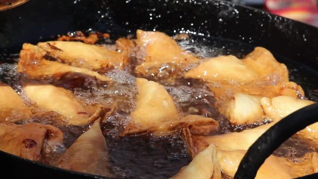 Steering And Turning Of Cooked Golden Brown Samosa Made Of Maida And Stuffed With Mix Of Mashed Potatoes Onions Peas Paneer Or Panir For Masala Chaat In Kadhai Full Of Hot Boiling Oil