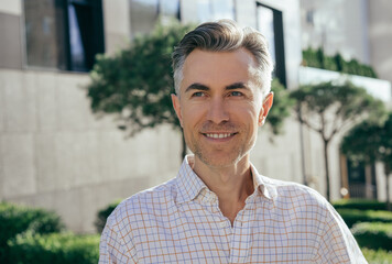 Handsome mature businessman standing on the street. Close up portrait of smiling manager. Successful business concept