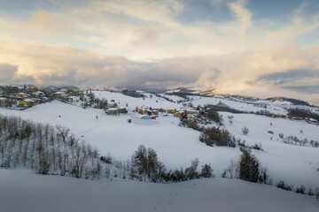 Aerial panoramic view of hills covered with snow at sunset