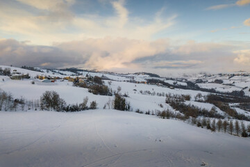 Aerial panoramic view of hills covered with snow at sunset