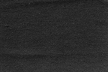 Cardboard black abstract texture close-up. Dark old paper background. Grunge concrete wall. Vintage blank wallpaper.
