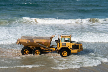 Heavy yellow dump truck working on the sea beach in Tel Aviv, Israel