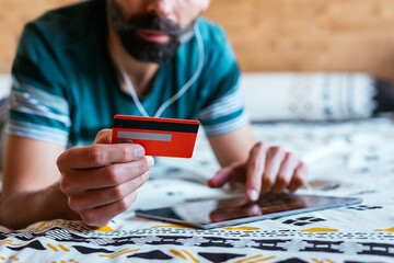 Close up hand holding credit card and shopping online on bed.