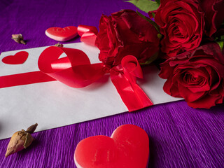 Red roses red hearts next to rosebuds and card with ribbon on background