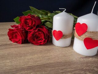 Red roses next to white candles and red hearts
