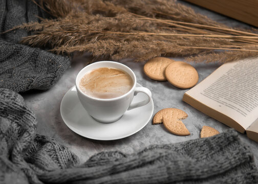 Cappuccino and bisquit cozy flat lay with book and dry reeds