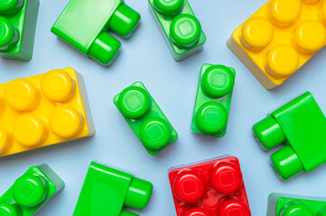 Multicolored plastic kids constructor on blue background. Colored children's bricks for construction. Flat lay top view copy space. Plastic building blocks background. Developing toys, game