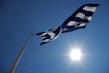 Flaga Grecji na wietrze na tle nieba pod słońce, Akropol, Ateny, Grecja / Greek flag waving in the wind against the sky and the sun, Acropolis, Athens, Greece