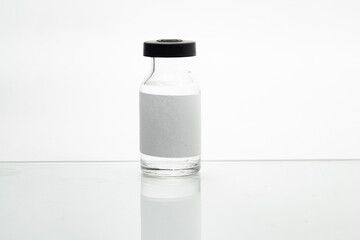 Vidro de vacina sobre a superfície branca de uma mesa.