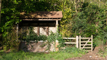 Old dilapidated bus shelter or shack in countryside with gate beside