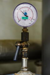 Circular analog pressure gauge with scale on the pipe.