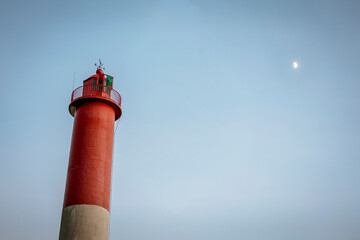 Un phare et la lune au loin