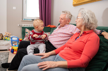 Senior couple with their little grandchild resting at home