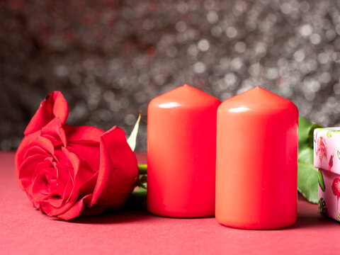 Red big rose which is next to two red candles which on white
