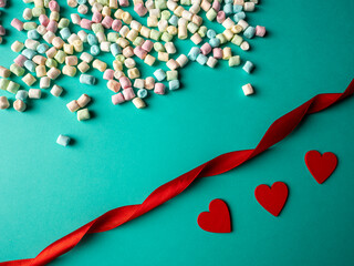 Three red hearts and multicolored candies, and between them lies a red ribbon