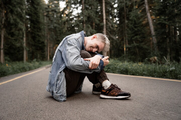 an unusual young guy with gray hair sits on the ground and laughs out loud