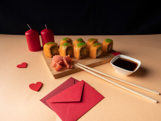 A lot of yellow sushi on a board and two red candles and two red envelopes
