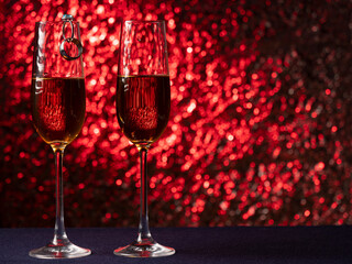 Two glasses of champagne stand on a blue surface with each other