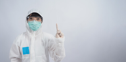Doctor Gesture. Asian woman doctor in PPE suit or Personal Protection Equipment gesturing and point out. white medical rubber gloves. goggles glasses and green N95 mask to protect pandemic coronavirus
