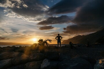 Silhouette of man over sunset on the sea and mountains background