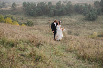 Romantic, young and happy caucasian couple in wedding clothes on the background of beautiful nature. Love, relationships, romance, happiness concept. Bride and groom traveling  together.