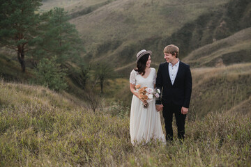 Romantic, young and happy caucasian couple in wedding clothes on the background of beautiful nature. Love, relationships, romance, happiness concept. Bride and groom traveling  together.