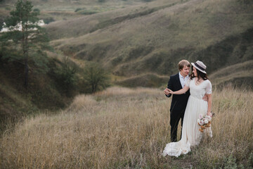 Romantic, young and happy caucasian couple in wedding clothes on the background of beautiful nature. Love, relationships, romance, happiness concept. Bride and groom traveling  together.
