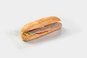 baguette with ham, tomatoes and herbs on a light background