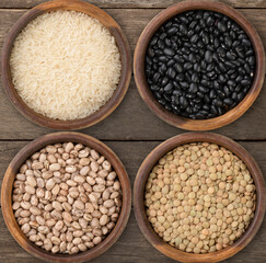 Four assorted grains in bowls over wooden background