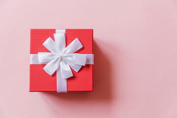 Christmas New Year birthday valentine celebration present romantic concept. Simply minimal design red gift box isolated on pastel pink colorful background. Flat lay top view, copy space