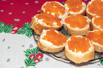 a plate of sandwiches with red caviar on a New Year's tablecloth