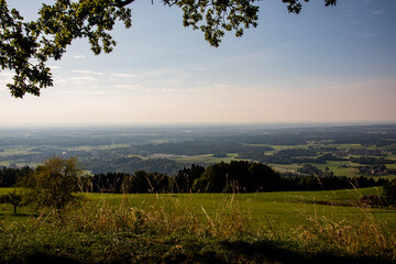Obraz premium A beautiful view of a small bavarian village in the foothills of the Alps, green rolling hills and blue sky - Bavarian Alps, Rosenheim, Bavaria, Germany