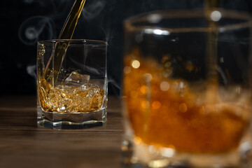 Whiskey drinks on wood with ice cubes and splash