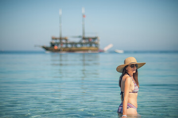 A young woman in the sea, a pirate ship behind her